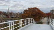 View from a bridge with autumn trees and a cloudy sky in the background.