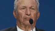 Lawrence H. Summers, looking serious while speaking at a podium with a microphone.
