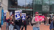 Picketers holding signs march outside the Smith Campus Center, advocating for labor rights.