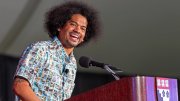 A man smiles while speaking at a podium with a Harvard logo.