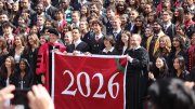 A large group of people poses together, holding a banner for the year 2026.