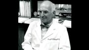 Black and white photo of Joseph Murray in a white lab coat sitting in an office.
