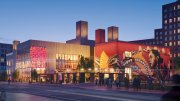 Vibrant urban scene at dusk featuring a mural on a building and illuminated structures.