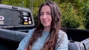 A woman with long hair stands confidently with crossed arms next to a pickup truck.