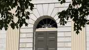 Historic building entrance featuring tall columns and a rounded arch doorway.