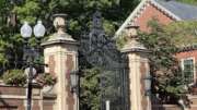 Morgan gate with brick pillars, surrounded by greenery and historic architecture.