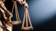 Close-up of a bronze scale symbolizing justice, with soft lighting in the background.