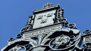 Ornate wrought iron gate detail against a clear blue sky.