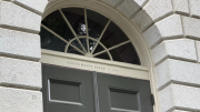Arched doorway with a decorative window above, labeled "University Hall," surrounded by stone.