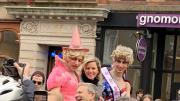 Elizabeth Banks looks at the camera as she rides in a convertible with two members of the Hasty Pudding Theatricals.