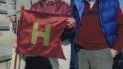 Alumnus Paul Lee ’46 carries the (replica) Little Red Flag at the 2012 Harvard-Yale game. Steve Goodhue ’51 is beside him; Spencer Ervin ’54 and Jeff Lee ’74 stand behind.