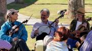 Two fiddlers and a banjo player take a break during an outdoor performance.