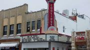 Photo of the exterior of Coolidge Corner Theater, with its vertical red neon sign.