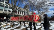 Demonstrators hold up a sign that reads, "Shame on Harvard." 