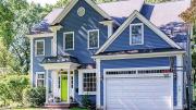 Exterior of blue house with garage surrounded by greenery