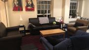 Photograph of the author's Harvard dorm room with chairs, sofa, posters