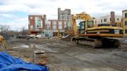 A public park is under construction at the intersection of Memorial Drive and Western Avenue. In the background, recently completed 10 Akron Street houses graduate students and other University affiliates.