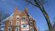 A Divest Harvard sign hangs from the windows of Mass. Hall.