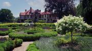 Wide view of formal gardens with a historic mansion in the background