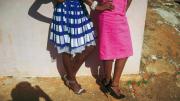 The lower halves of two women stylishly dressed in bright colored skirts and high heels