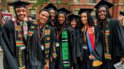 Harvard undergraduates standing happily in Commencement regalia 