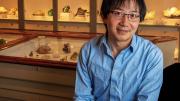 Roger Fu sits in front of a display case of rock samples