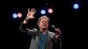 Jimmy Tingle holding a microphone and performing on stage 