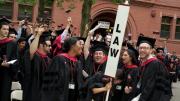Harvard Law School graduates celebrate, gavels in hand.