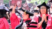 Graduate School of Education degree recipients wave composition books, to be donated to local schools
