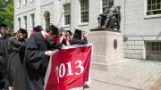 The traditional doffing of caps to John Harvard as seniors pass him by