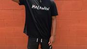 Elijah DeVaughn '21 in black shirt bearing the word "melanin," stands with his right fist raised