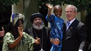 George W. Bush, speaking about PEPFAR (the global AIDS initiative) and holding Baron Mosima Loyiso Tantoh, with Kunene Tantoh, the boy’s mother, then suffering from AIDS, and Bishop Paul Yowakim, May 30, 2007, the White House