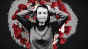 A person wearing a mask standing in front of the COVID virus