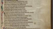 A page of medieval script with brightly colored initial letter and drawings in the margins
