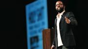With a front page from <i>The Onion</i> projected in the background, Thurston emcees the 2009 SXSW Interactive Web Awards.