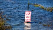 A traffic sign with the words "Stop Road Closed" submerged in several feet of water