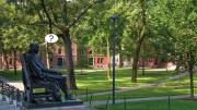 Photograph of John Harvard statue, Harvard Yard, with cartoon balloon question mark, about uncertainties surrounding the fall semester
