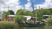 A boat, sails furled, docked near the Essex Historical Society and Shipbuilding Museum. 