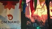 The entrance to Om Namo Yoga Studio, with prayer flags hanging high against a twilight sky.