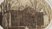 Old photograph of Hollis Hall with students gathered around the large “Rebellion Tree” in front of the building.