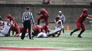 Harvard running back Aaron Shampklin hops over a Harvard teammate with a football in hand.