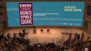 Audience members sit in a large auditorium at the start of the conference