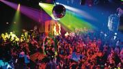 A disco ball and DJ overlook the <i>Donkey Show</i> audience as cast members enact a scene.