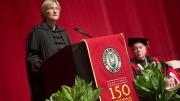 Father William Leahy, Boston College president, looks on as Drew Faust delivers her address at the Boston College sesquicentennial celebration.
