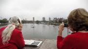 Julie Tonks, camera at the ready, and Abbie Bingham Endicott scan the river for their husbands' boat.