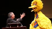 President Bacow and Big Bird talking on stage