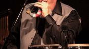 Percussionist Manolo Badrena playing a percussion instrument.