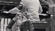 Jazz artist Walter Blanding playing the saxophone on his back on the floor, "demonstrating" styles of John Coltrane, 2002