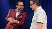 A magician and comedian doing a card trick with an audience member