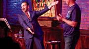 Greenbaum excitedly gesturing toward an audience member on stage at the Comedy Cellar